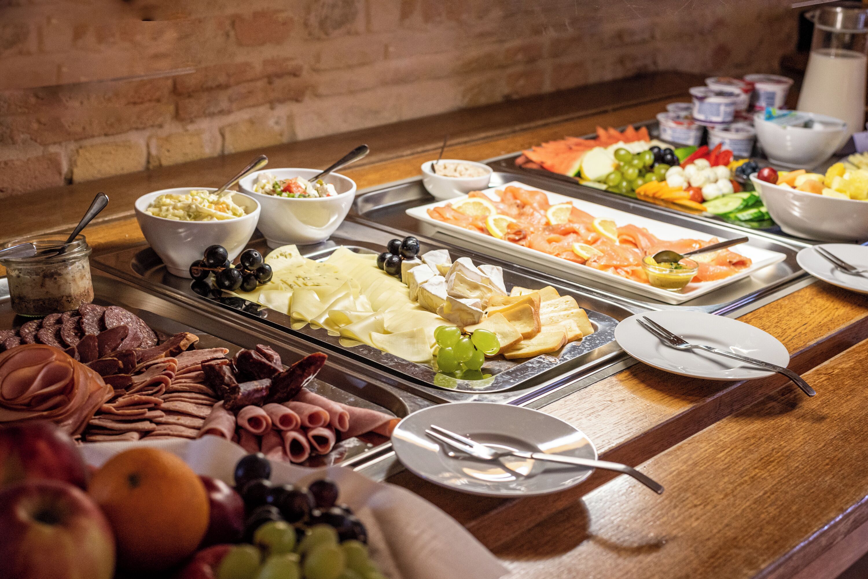 Ein reichhaltiges Buffet mit einer Auswahl an Speisen, darunter Fleisch, Käse, Obst und Gemüse.