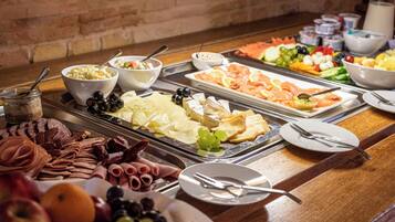 Ein reichhaltiges Buffet mit einer Auswahl an Speisen, darunter Fleisch, Käse, Obst und Gemüse.