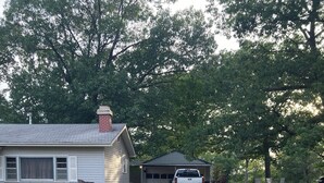 A gravel driveway leading to a garage and a small house with a chimney. - Pomme de Terre Lake Getaway: 5 Min walk to lake  – 15 Min drive to Lucas Oil (Hermitage)