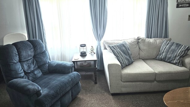 A living room with a blue armchair, a beige sofa, and a small table with a lamp. - Pomme de Terre Lake Getaway: 5 Min walk to lake  – 15 Min drive to Lucas Oil (Hermitage)