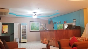 Un hall de hotel con una recepción, un refrigerador y un área de descanso con sofás.