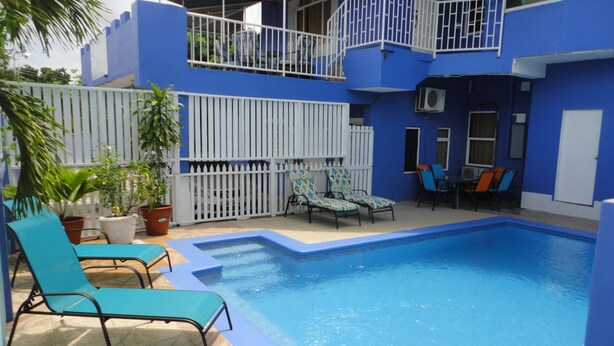Un área de piscina con sillas de descanso y un patio cercado.