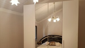 Une chambre avec une armoire à miroir, un lit recouvert d’une couvre-lit à motifs et un lustre.