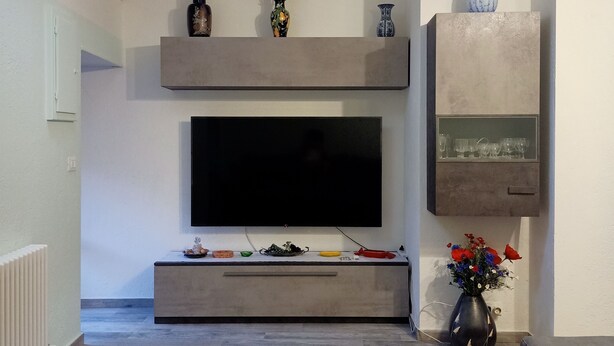 Un salon moderne avec un téléviseur à écran plat, un canapé, une table basse, un tapis à motifs et des vases décoratifs.