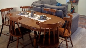 Un espace repas comprenant une table et des chaises en bois, un canapé gris et un luminaire suspendu au plafond.