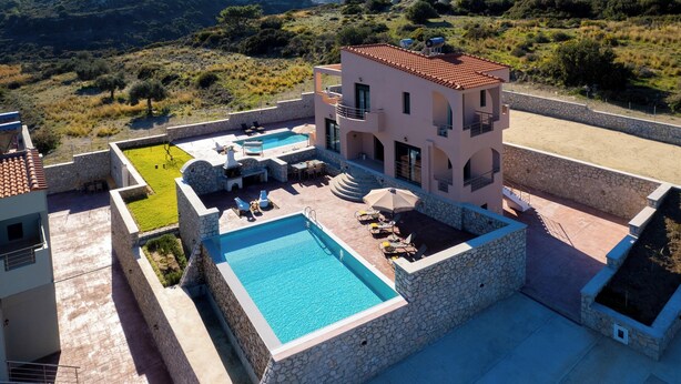A multi-story building with a swimming pool, outdoor seating, and a stone retaining wall. - Alki Slow Living - Alkinoe (Afandou)