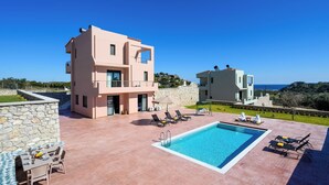 A modern multi-story building with a swimming pool, outdoor seating, and a view of the sea. - Alki Slow Living - Alkinoe (Afandou)