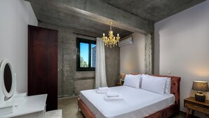 A bedroom with a bed, a vanity with a mirror, a chandelier, and an air conditioning unit. - Alki Slow Living - Alkinoe (Afandou)