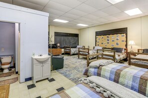 Un dormitorio con cuatro camas de madera, un lavamanos blanco, una pizarra y un tablón de anuncios con fotografías.