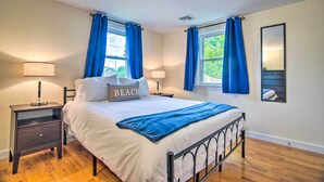 Une chambre à coucher comprenant un lit, deux tables de chevet, une commode, une fenêtre avec des rideaux, un miroir et une lampe.