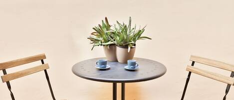 A round table with two chairs, a potted plant, and two cups.