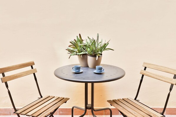 A round table with two chairs, a potted plant, and two cups.