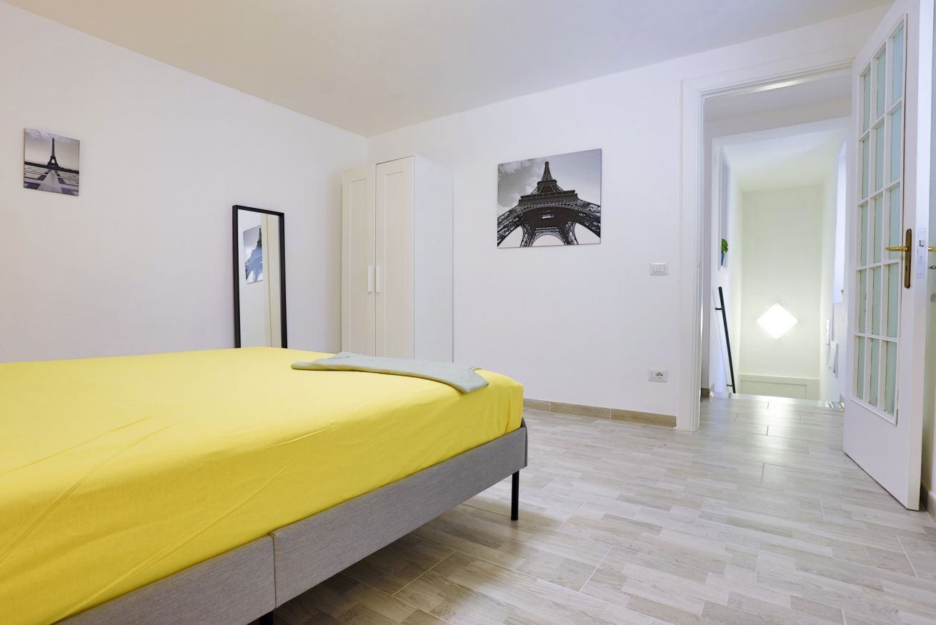 A bedroom with a bed, a door, and a hallway.