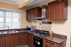 Une cuisine avec des meubles de rangement en bois, une cuisinière à gaz, un four à micro-ondes et un évier.