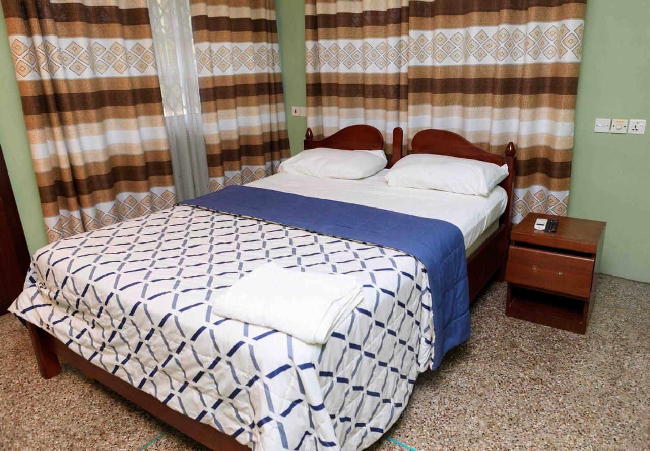 Une chambre à coucher avec un lit, des rideaux, une table de chevet et une commode.