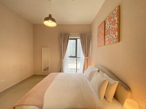 Un dormitorio con cama, lámpara colgante, ventana con cortinas y espejo montado en la pared.