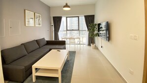 Un salon moderne avec un canapé gris, une table basse blanche et un téléviseur fixé au mur.