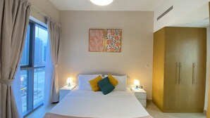 Une chambre d’hôtel avec un grand lit, deux lampes de chevet, une fenêtre avec des rideaux et une armoire.