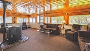 A cozy cabin interior with a wood stove, comfortable seating, and large windows. - ‘Mtn Gate Guest House’ ~ 6 Mi to Shasta Lake! (Redding)