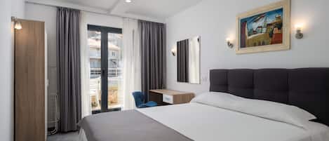 Una habitación de hotel moderna con una cama grande, un escritorio, una silla y un balcón con cortinas.