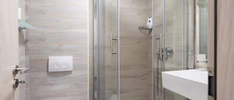 A modern bathroom with a glass-enclosed shower, a toilet, and a sink.