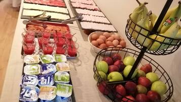 A buffet table with various food items including meats, cheeses, fruits, and beverages.
