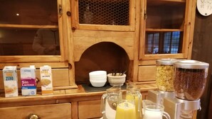 A breakfast setup with various dairy products, including milk and almond milk, and a juicer with fresh juice. - Hotel Villa de Vinuesa (Vinuesa)