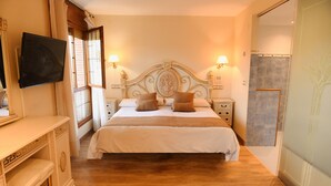 A bedroom with a large bed, bedside tables, a TV mounted on the wall, and a sliding door leading to a bathroom. - Hotel Villa de Vinuesa (Vinuesa)