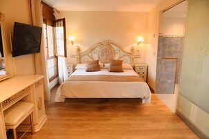 Un dormitorio con una cama grande, mesitas de noche, un televisor montado en la pared y una puerta corredera que da al baño.