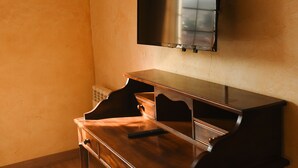 A room with a wooden desk, a flat-screen TV mounted on the wall, and a radiator below the TV. - Hotel Villa de Vinuesa (Vinuesa)