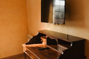 Una habitación con un escritorio de madera, un televisor de pantalla plana montado en la pared y un radiador debajo del televisor.