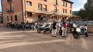 A row of parked motorcycles in front of a building with multiple balconies and windows. - Hotel Villa de Vinuesa (Vinuesa)
