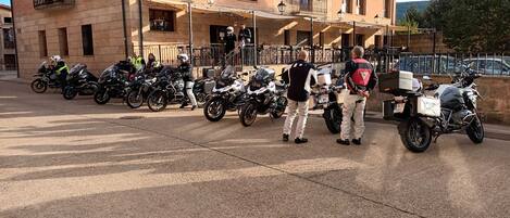 A row of parked motorcycles in front of a building with multiple balconies and windows.