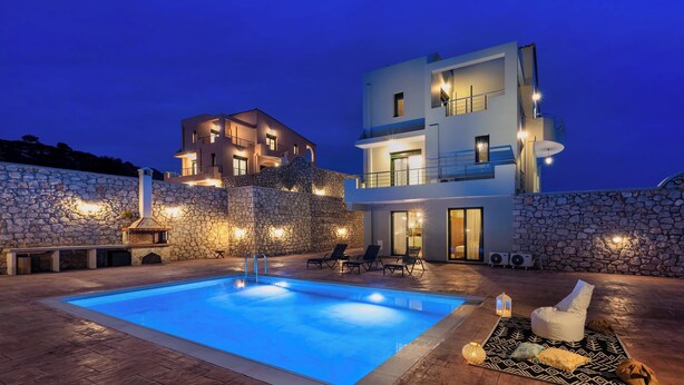 Ein modernes Haus mit Swimmingpool, Steinmauern und Sitzgelegenheiten im Freien.