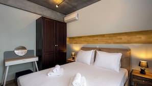 Ein Hotelzimmer mit Bett, Schreibtisch, Kleiderschrank, Klimaanlage und zwei Nachttischlampen.