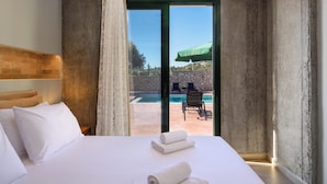 Ein Hotelzimmer mit Bett, Blick auf einen Außenpool und einer Steinwand.