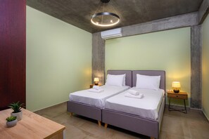 A double bed with two bedside tables, a wooden desk, and a potted plant.