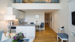 A modern apartment with a kitchen, dining area, and a balcony. - Galerieappartement zur Südseite (Juist)
