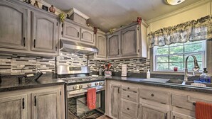 A kitchen with light wood cabinets, a stainless steel range, and a window with a view of greenery. - Cozy Hale Home Between Long & Loon Lakes! (Hale)