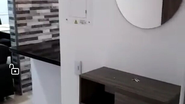 A modern kitchen with a built-in wooden cabinet, a round mirror, and a wall-mounted electrical outlet.