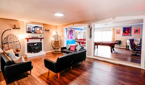 Relax in this inviting living room with a fireplace, comfortable seating, and a pool table.