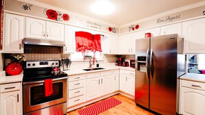 Une cuisine moderne avec des armoires blanches, des appareils en acier inoxydable et des touches de couleur rouge.