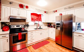 Enjoy cooking in this well-equipped kitchen with stainless steel appliances, white cabinetry, and a red rug.