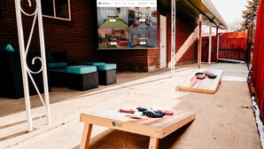 Un espace extérieur aménagé avec une table et des bancs en bois, un mur en briques et une clôture rouge.