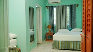 A room with a bed, a nightstand, a lamp, and a window with curtains. - Queen room at Bellissimo (Scarborugh)