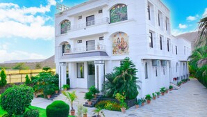 A multi-story building with a white facade, large windows, and a balcony. - The Pure Nature Hotel (Rajgarh)