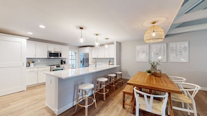 A modern kitchen with white cabinetry, a central island with stools, and pendant lighting.