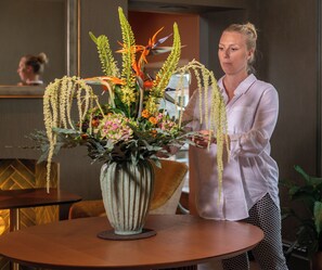 A woman arranging a floral centerpiece on a round table in a room with a modern interior design.