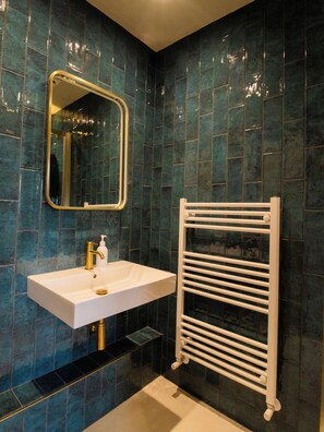 A bathroom with a white sink, gold faucet, and a mirror.