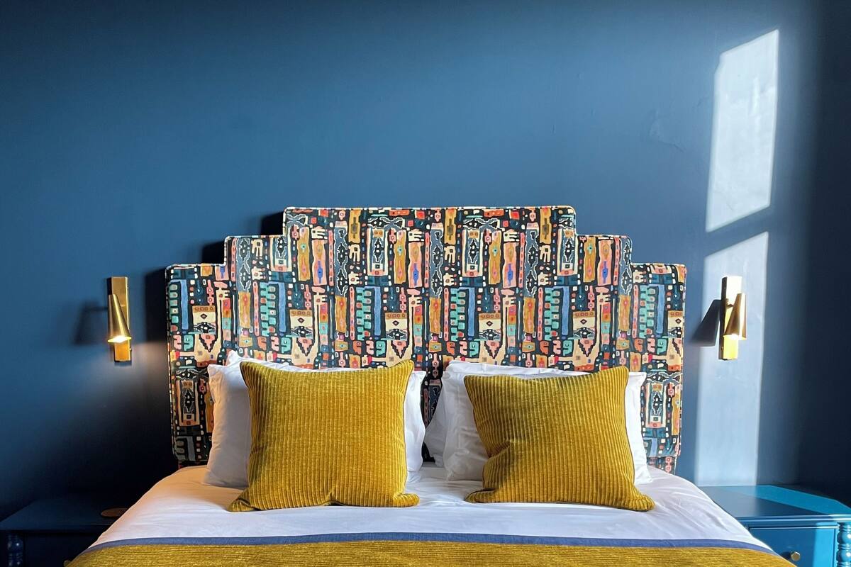 A bed with a patterned headboard, yellow pillows, and a gold-colored bedspread.